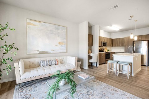 A living room with a white couch and a painting on the wall.