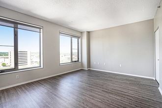 The Plaza Apartments In Grand Rapids, MI Spacious Living Room With Wood Style Flooring an empty living room with three large windows