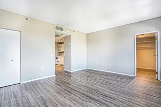 The Plaza Apartments In Grand Rapids, MI Spacious Living Room With Wood Style Flooring an empty living room with a kitchen in the background
