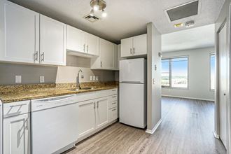 The Plaza Apartments In Grand Rapids, MI Premium Kitchen With Wood Style Flooring a kitchen with white cabinets and a white refrigerator