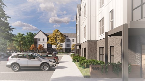 A street view with cars and a white building with a black roof.