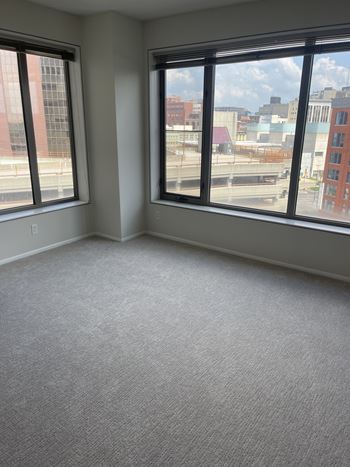 A room with two large windows overlooking a cityscape.