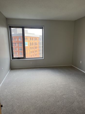 A room with a carpeted floor and a window overlooking a cityscape.