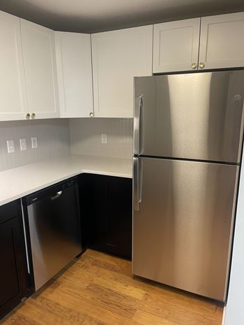 A kitchen with a stainless steel refrigerator and black cabinets.