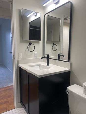 A bathroom with a sink, mirror, and toilet.
