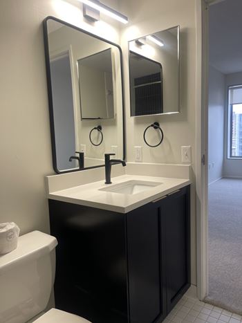 A bathroom with a sink, toilet and mirror.