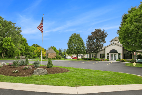 a flagpole with an american flag in front of a building with a parking lot
