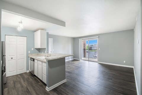 a kitchen and living room with a sliding glass door leading to a balcony