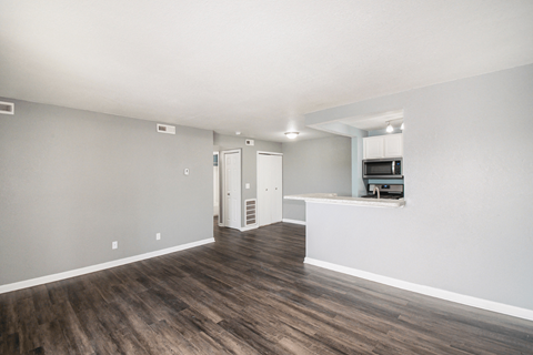 a living room with hardwood floors and a kitchen in the background