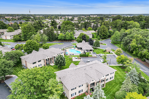 an aerial view of a large white house with a pool in the middle of a grassy