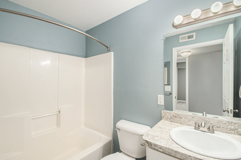 a bathroom with a white toilet next to a white bathtub