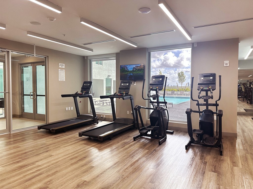 a gym with cardio equipment and a large window with a view of the pool  at Douglas Enclave, Miami, 33125