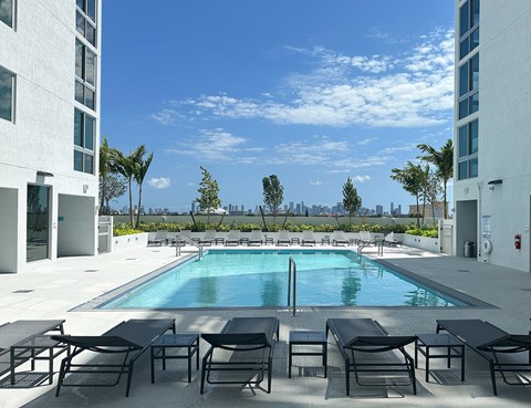 an outdoor pool with lounge chairs and a view of the Miami skyline an outdoor pool with lounge chairs and a view of the Miami skyline at Douglas Enclave, Miami, FL, 33125