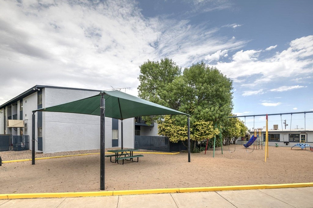 a playground in front of a white building with a blue sky in the background
