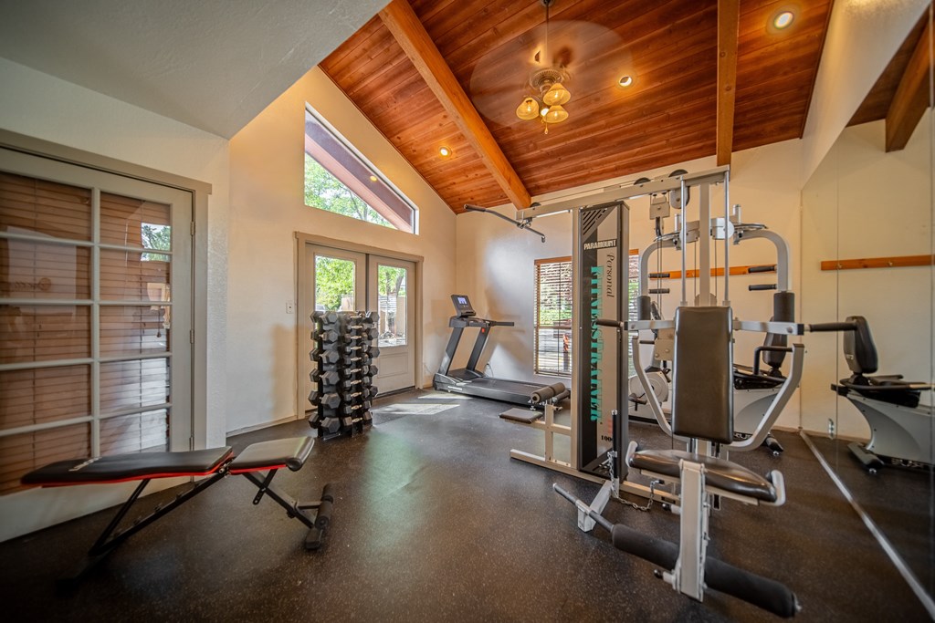 A home gym with a variety of equipment including a treadmill, weights, and a bench press.