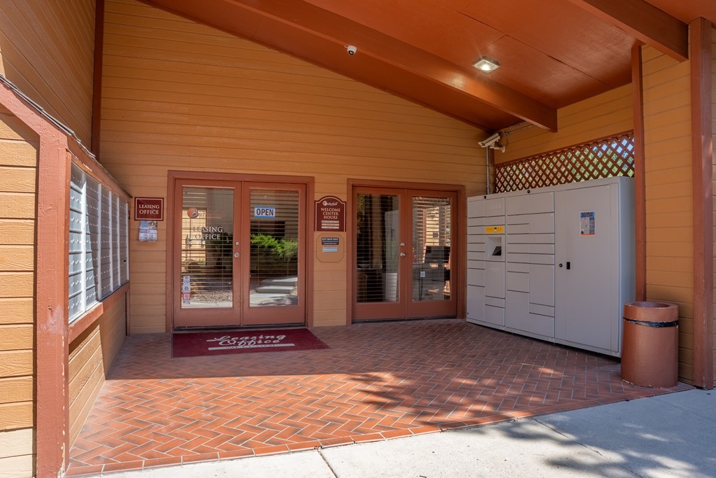 The image shows a building entrance with a red mat on the ground and a white cabinet to the right.