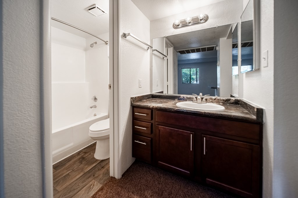 A bathroom with a brown counter top and a white toilet.