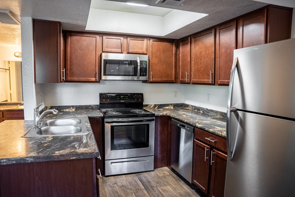 A kitchen with a stainless steel refrigerator, microwave, oven, and sink.