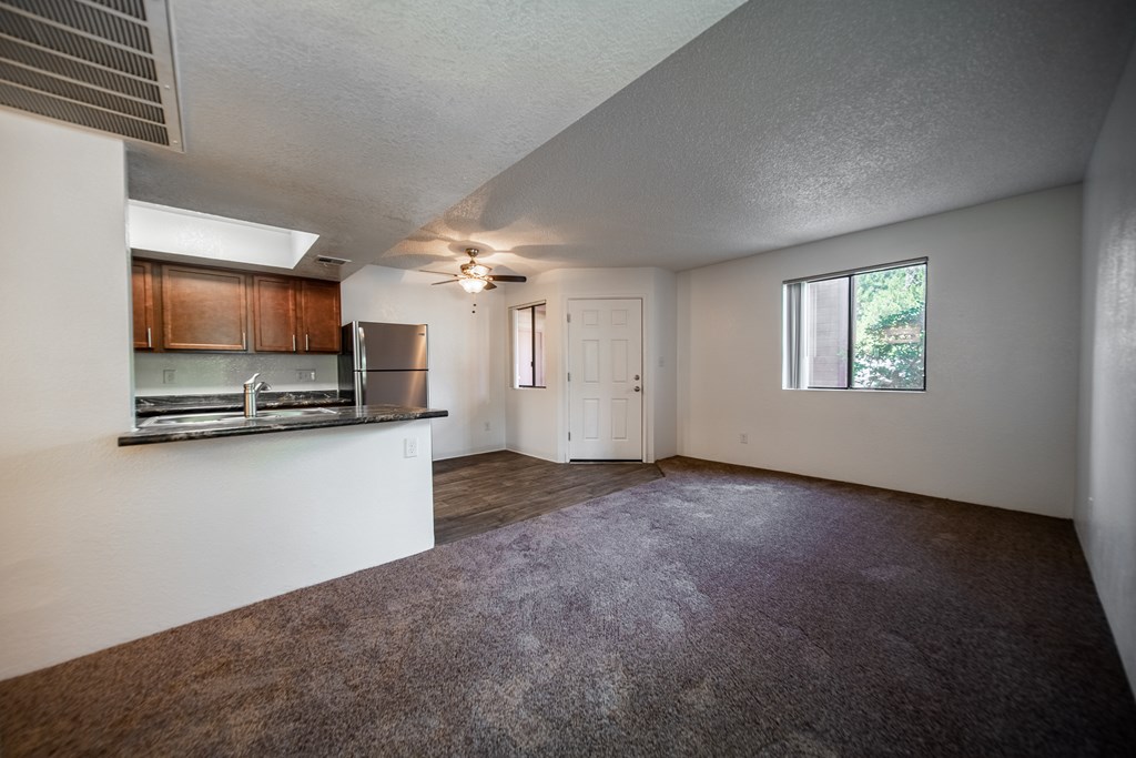 A room with a carpeted floor and a ceiling fan.