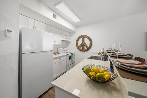 A kitchen with a bowl of fruit on the counter.