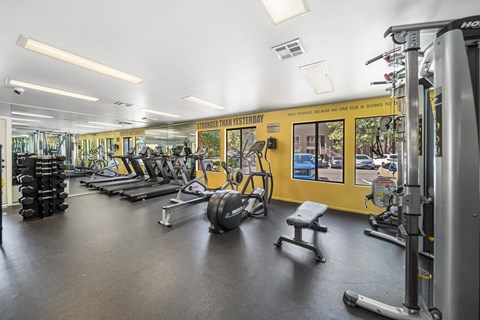 A gym with a variety of equipment including treadmills, weights, and exercise machines.