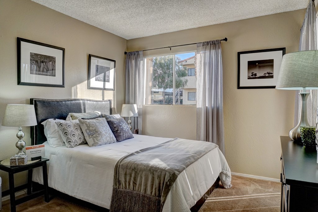 A bedroom with a large bed and a window with curtains.
