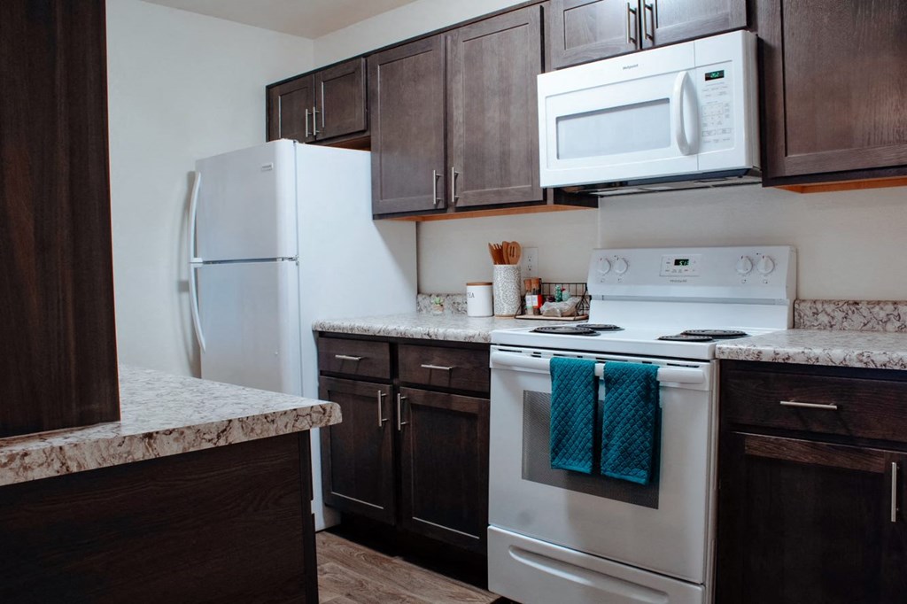 a kitchen with white appliances and dark wood cabinets