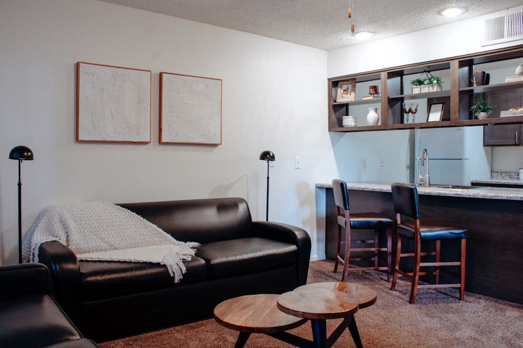 a living room with a couch a table and a kitchen in the background