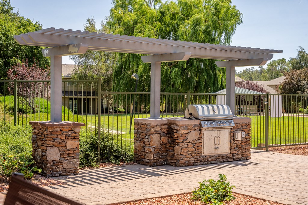 A white pergola is supported by two stone pillars.