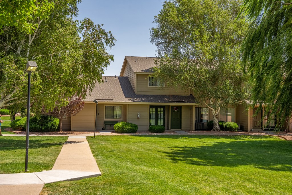 A house with a brown roof and a green lawn in front.
