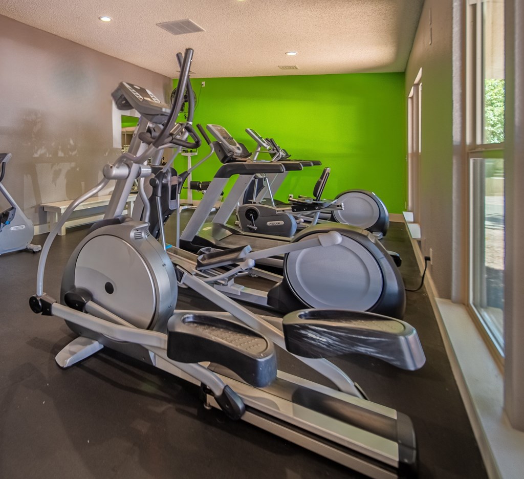 A row of exercise bikes are lined up in a row.