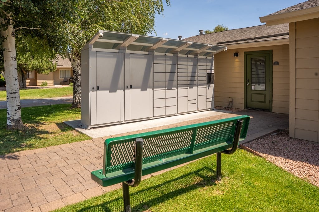 A green bench is in front of a storage shed.