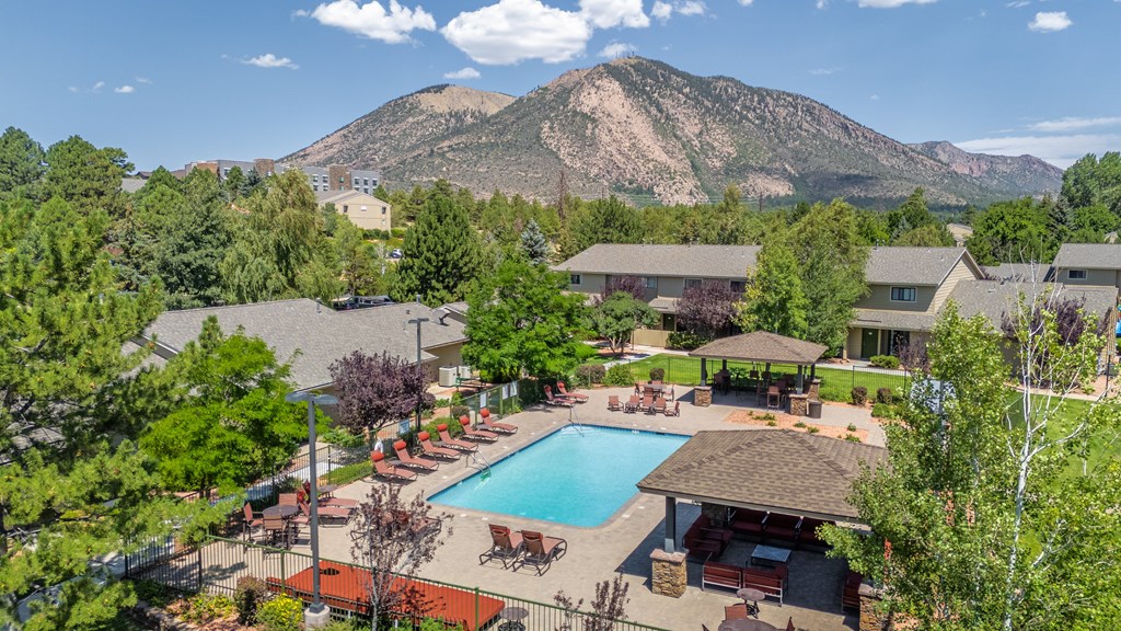 A large swimming pool surrounded by a patio and a mountain in the background.