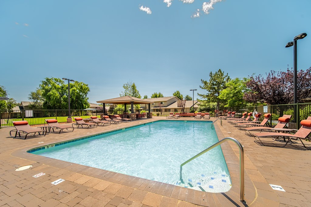 A large swimming pool surrounded by lounge chairs and trees.