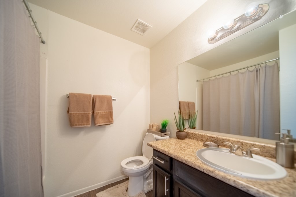 A bathroom with a toilet, sink, and towels.