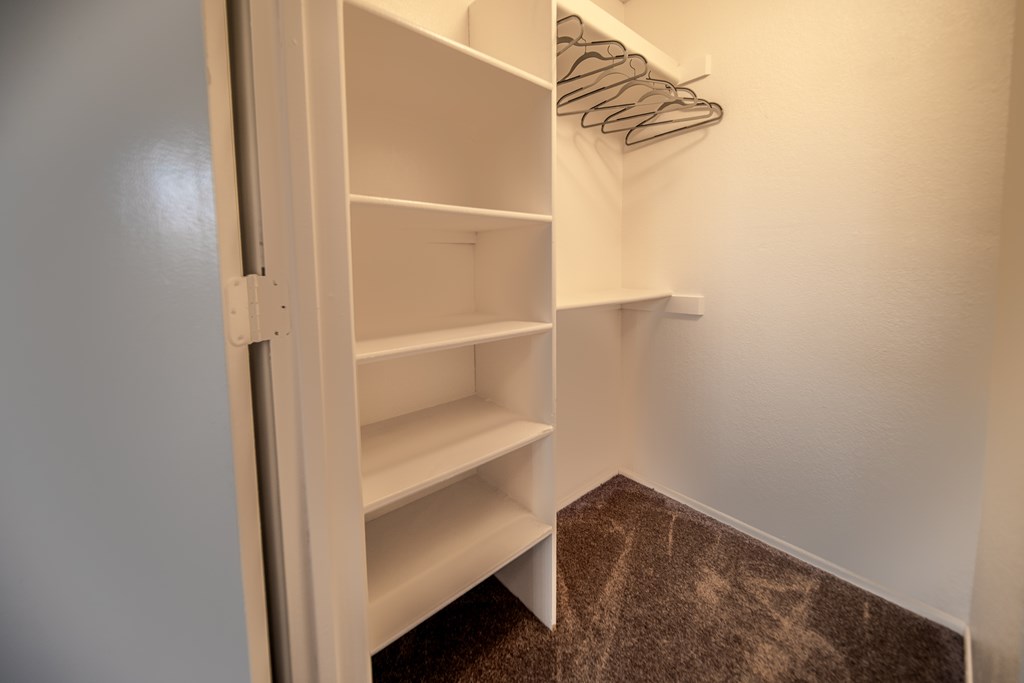 A white closet with shelves and hangers.