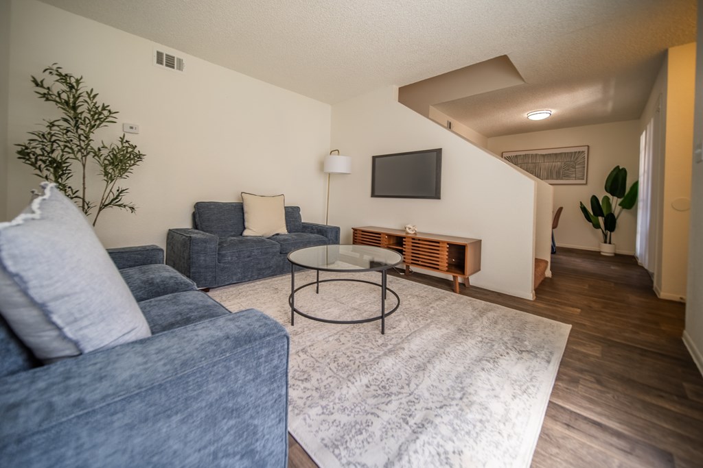 A living room with a blue couch and a white rug.