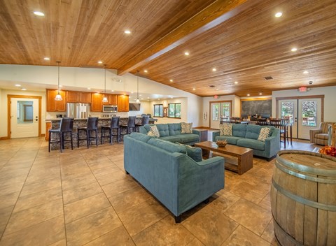 A large room with a wooden ceiling and a wine barrel on the floor.