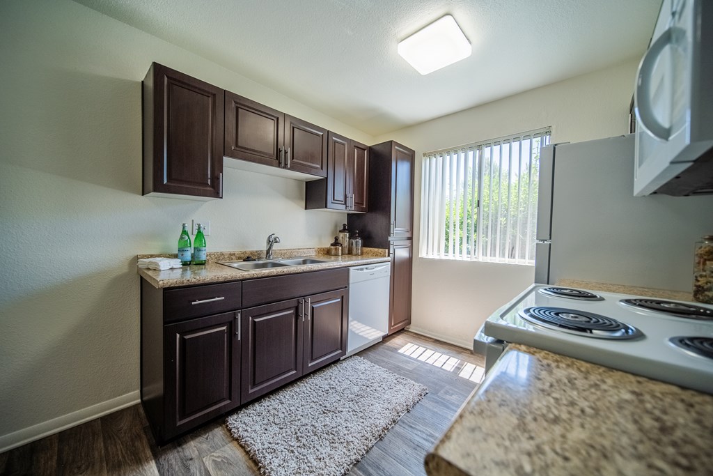 One Bedroom A kitchen with brown cabinets and a white stove top oven.