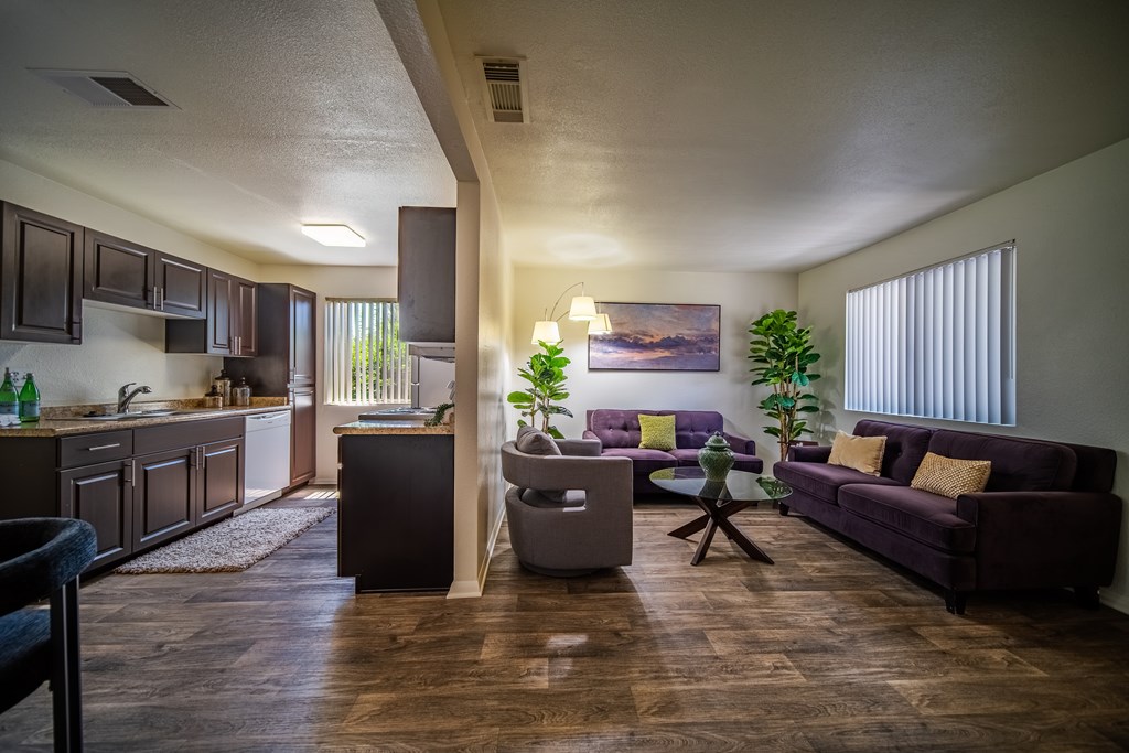 A living room with a purple couch and a painting on the wall.