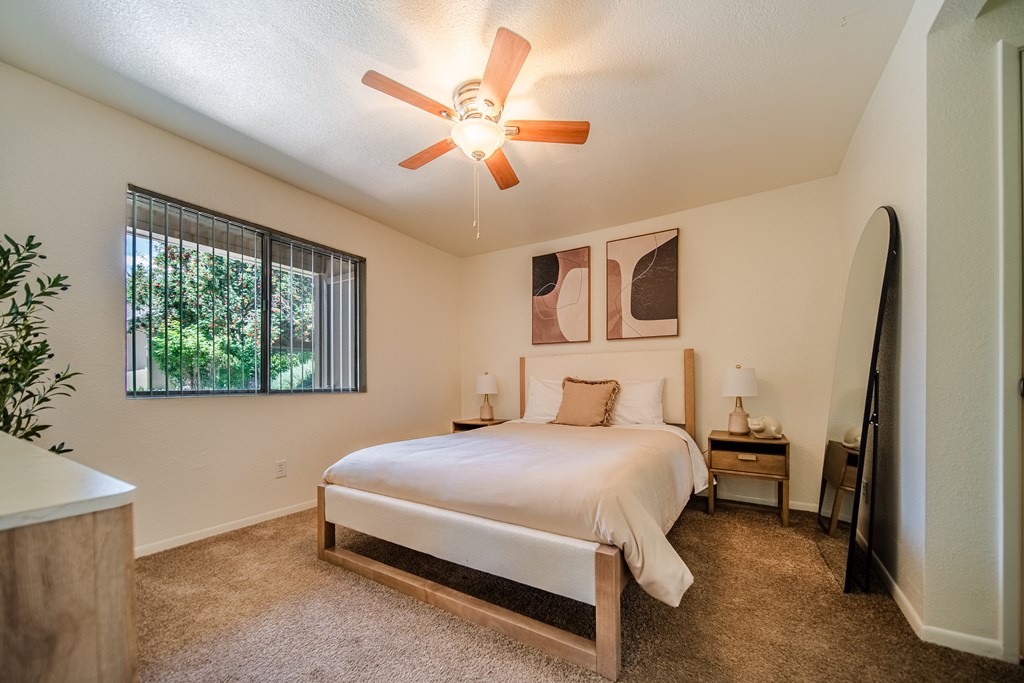 A bedroom with a large bed and a ceiling fan.
