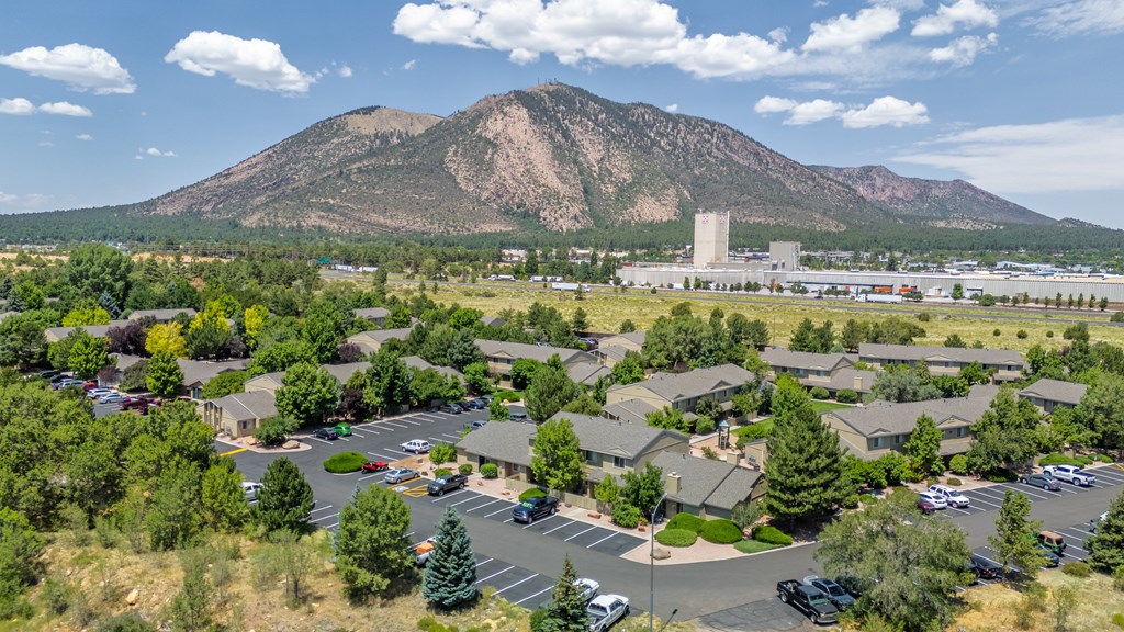 A mountain is in the background of a parking lot with cars parked in it.