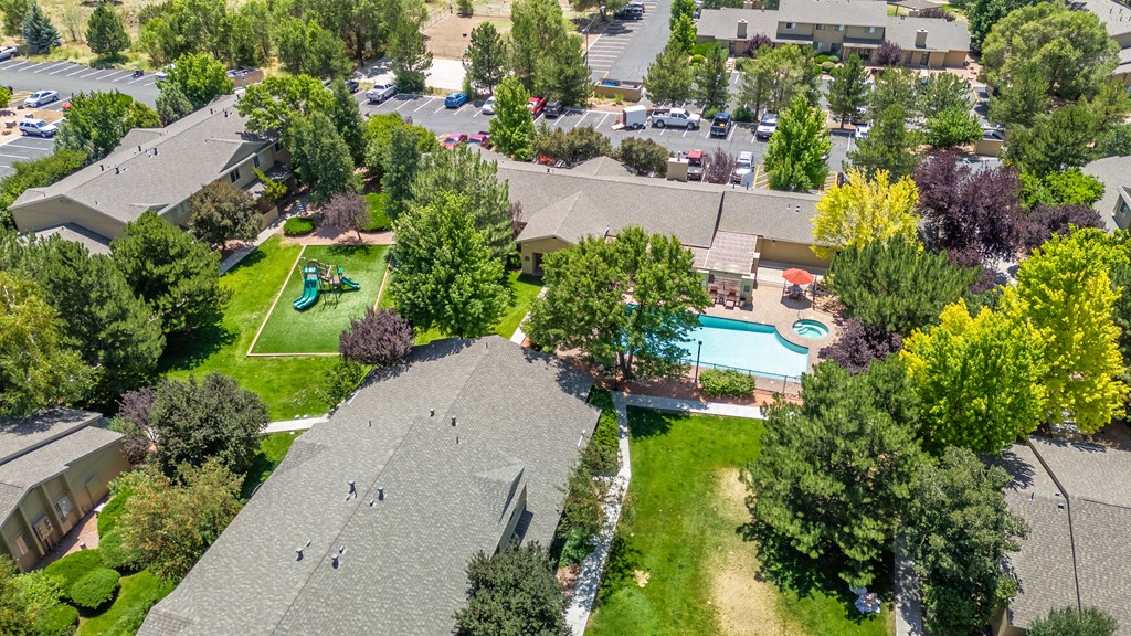 A bird's eye view of a residential area with houses, trees, and a pool.