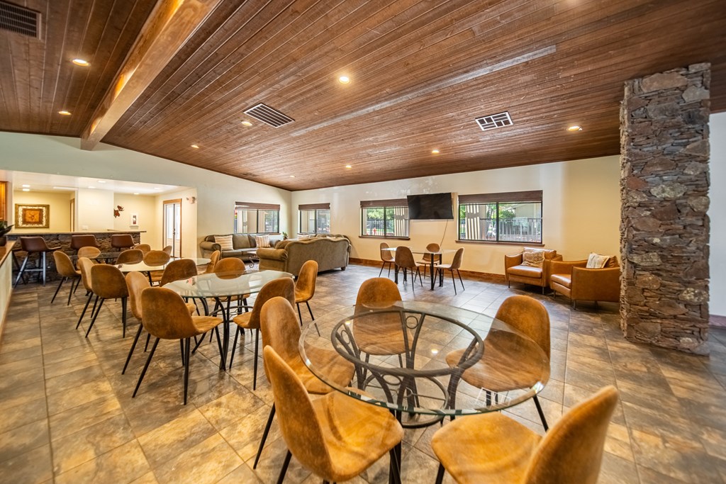 A large room with a stone pillar and wooden chairs.