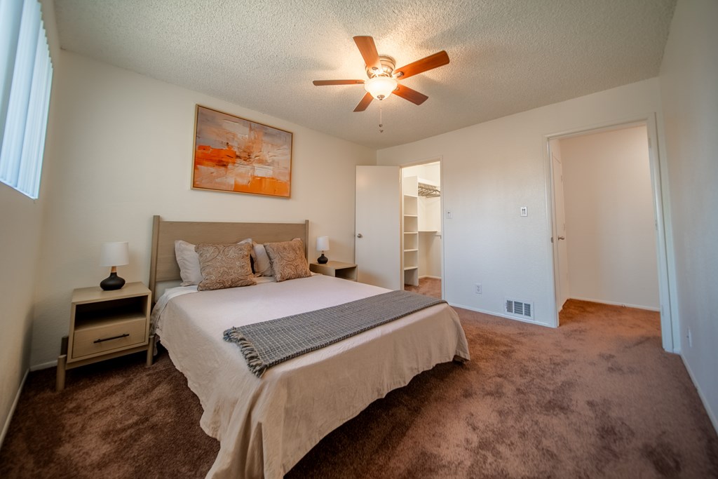 A bedroom with a bed, nightstands, and a painting on the wall.