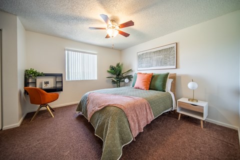 A bedroom with a bed, chair, and plants.