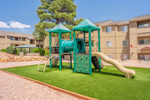 A playground with a green slide and a blue roof.