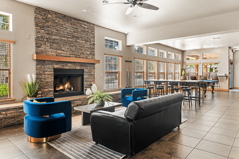 A living room with a stone fireplace and blue chairs.