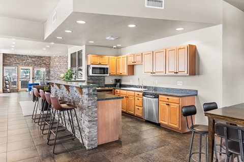 A kitchen with a bar area and wooden cabinets.