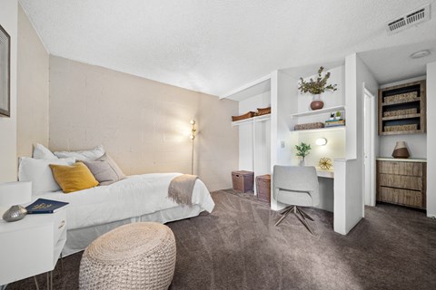 A bedroom with a white bed and a grey chair.